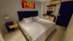 a bedroom with a white bed and a television at Hotel Boutique Calle Grande in Valledupar