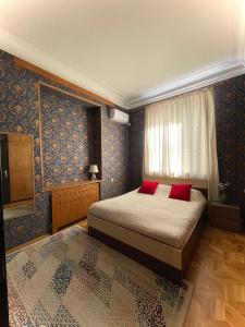 提比里斯的住宿－Check Inn Tbilisi，一间卧室配有一张带红色枕头的床