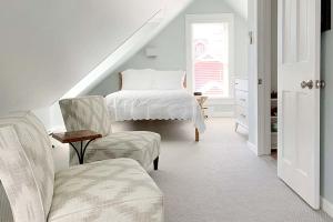 a white room with a bed and a chair at The Inn at Manchester in Manchester