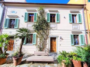 a white building with green shutters and a bench in front at Casa Franco in Marina di Campo