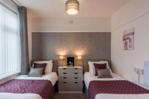 a bedroom with two beds and a dresser in it at The Fountaindale Skegness in Skegness