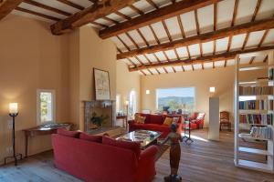 a living room with red couches and a fireplace at Poggio Tamantino, Villa con piscina in Maremma in Poggio Cavallo