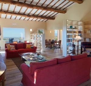 a living room with red couches and a table at Poggio Tamantino, Villa con piscina in Maremma in Poggio Cavallo