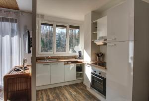 a kitchen with white cabinets and a sink and a window at Appartement Plage et JACUZZI Balnéothérapie Athis Mons in Athis-Mons
