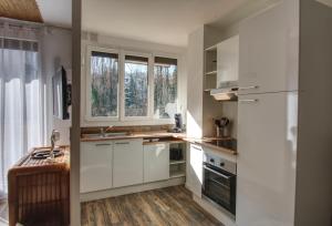 Una cocina con gabinetes blancos y un fregadero y una ventana. en Appartement Plage et JACUZZI Balnéothérapie Athis Mons, en Athis-Mons