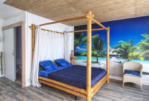 a bedroom with a canopy bed with blue pillows at Appartement Plage et JACUZZI Balnéothérapie Athis Mons in Athis-Mons