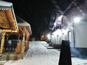 a snow covered street at night with lights at Maramures Landscape in Moisei
