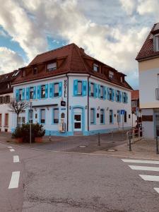 un bâtiment bleu et blanc avec un toit brun dans l'établissement Gästehaus Kronenstraße, à Schwetzingen