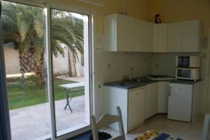 une cuisine avec des appareils électroménagers blancs et une porte coulissante en verre dans l'établissement GITE MEUBLE POUR 1,2,3,4 PERS AVEC PISCINE à PARTAGER, à Agde