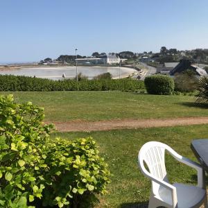 a white chair sitting in the grass next to a table at MAISON 6 pers belle vue mer PISCINE, plage à 40 m in Trévou-Tréguignec