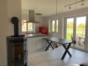 a kitchen with a stove and a table in it at Pfahlbau, Ferienwohnung für 4 Personen - Erwachsene oder Kinder - in DE FEERJENHUSEN am Haubarg von Vollerwiek, Fertigstellung April 2020 in Vollerwiek