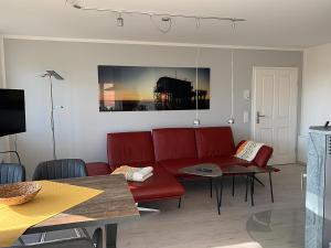 a living room with a red couch and a table at Pfahlbau, Ferienwohnung für 4 Personen - Erwachsene oder Kinder - in DE FEERJENHUSEN am Haubarg von Vollerwiek, Fertigstellung April 2020 in Vollerwiek