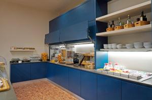 a kitchen with blue cabinets and food on display at Hotel Marconi in Sirmione
