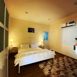 a bedroom with a white bed with two tables and two lamps at Al Reef Rest House in Al Khārī