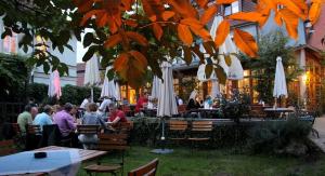 eine Gruppe von Menschen, die in einem Restaurant mit weißen Sonnenschirmen sitzen in der Unterkunft Gasthaus Sindel-Buckel in Feuchtwangen