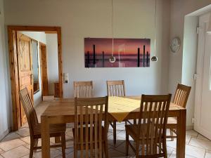 a dining room with a wooden table and chairs at Abendstille, Ferienwohnung für maximal 4 Erwachsene und 2 Kinder in DE FEERJENHUSEN am Haubarg von Vollerwiek in Vollerwiek