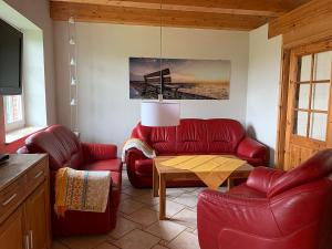a living room with red leather chairs and a table at Abendstille, Ferienwohnung für maximal 4 Erwachsene und 2 Kinder in DE FEERJENHUSEN am Haubarg von Vollerwiek in Vollerwiek