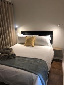 een slaapkamer met een groot bed met witte lakens en kussens bij The Haystack on Cowley in Johannesburg