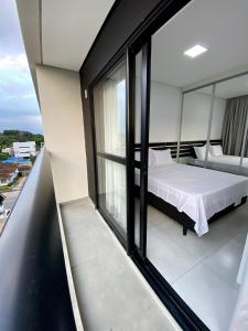 um quarto com uma cama numa varanda em MaxLoft - Apto novo Smart Tv, lavanderia em Joinville