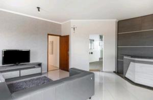een woonkamer met een televisie en een bank bij Nosso Hotel in Campo Grande