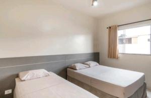 a bedroom with two beds and a window at Nosso Hotel in Campo Grande