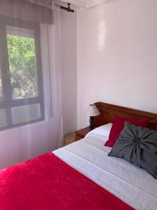 a bedroom with a red and white bed with a window at Apartamento la Ribera in Suances