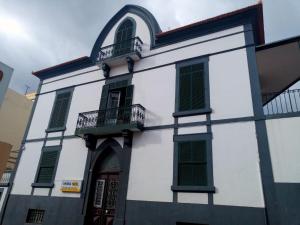 フンシャルにあるPensao Residencial Mirasolの白い建物(緑のシャッター、バルコニー付)