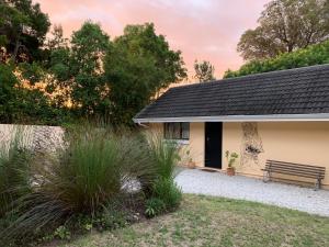 une maison avec un banc dans la cour dans l'établissement Garden Cottage in Ambiente Guest House, à Knysna