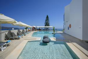 a swimming pool with lounge chairs and umbrellas at Hermes Sea View in Stalos