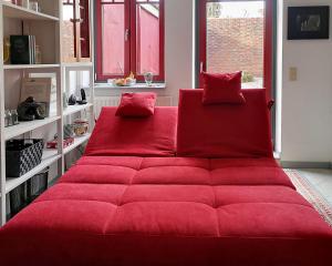 a red couch in a room with red pillows at Gemütliches Ferienhaus - ankommen und wohlfühlen in Husum