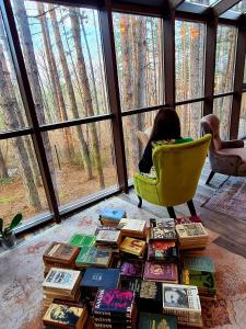 a person sitting in a chair with a pile of books at Вила АРБОРЕТУМ in Teteven