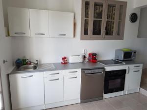 a kitchen with white cabinets and a sink at La Campagne in La Ciotat