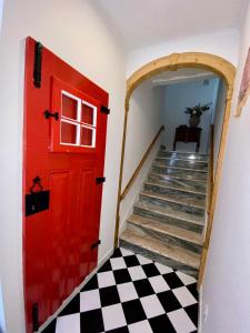 a red door in a hallway with a checkered floor at TikLiving in Ericeira