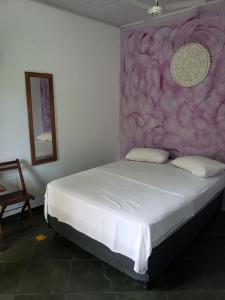 a bedroom with a large bed with a pink wall at Chales Terra Pura in Camburi