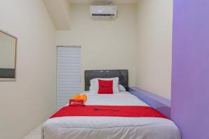 RedDoorz near Trans Studio Bandung 3 في باندونغ: غرفة نوم بسرير وبطانية حمراء وزرقاء