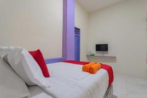 a bedroom with a bed with two orange towels on it at RedDoorz near Trans Studio Bandung 3 in Bandung