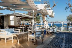 un patio con sedie, tavoli e ombrelloni di Seaside by Manos a Kamari