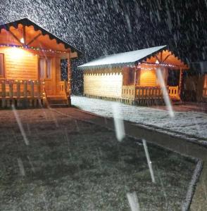 Cabaña de madera con nieve en el patio en Camping Farm Shelegur en Leskovik