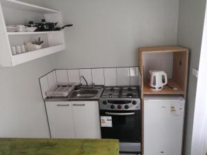 a small kitchen with a stove and white cabinets at Cabañas Simón y kiara in Los Vilos +13 photos