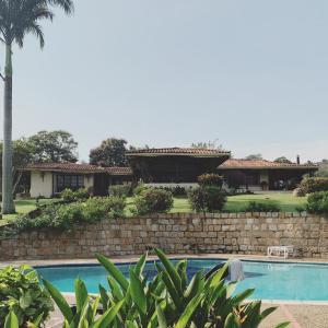 a house with a stone wall and a swimming pool at Villa Calusa in Villeta