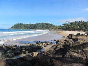 uma praia com algumas rochas e o oceano em Casa do Miguel em Itacaré