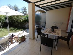 a patio with a table and chairs and an umbrella at Vivere Apartment Barbati Beach in Barbati