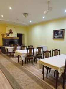 een eetkamer met tafels en stoelen en een open haard bij Панський Двір in Neslukhov