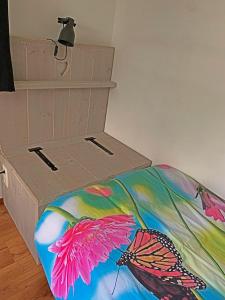 a bed with a butterfly blanket and a box at Christinahoeve Hooiberg #5 in Boskoop