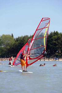 eine Gruppe von Menschen am Strand mit Windsurfen in der Unterkunft Apartments in Peschiera del Garda 22109 in Peschiera del Garda