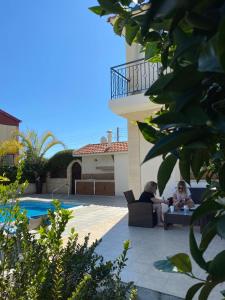 two women sitting in chairs next to a swimming pool at EPISKOPI VILLA, Luxury 4 Bedroom with Pool - Limassol in Limassol