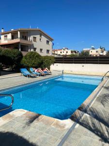 una piscina con 2 personas en sillas junto a un edificio en EPISKOPI VILLA, Luxury 4 Bedroom with Pool - Limassol, en Limassol