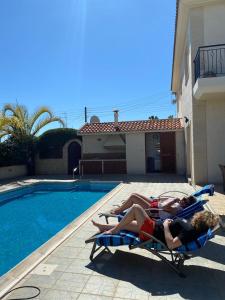 two people laying on a lawn chair next to a pool at EPISKOPI VILLA, Luxury 4 Bedroom with Pool - Limassol in Limassol