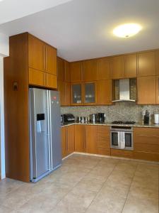 a kitchen with wooden cabinets and a stainless steel refrigerator at EPISKOPI VILLA, Luxury 4 Bedroom with Pool - Limassol in Limassol