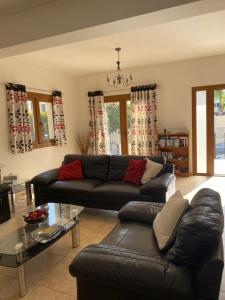 a living room with a black leather couch and a table at EPISKOPI VILLA, Luxury 4 Bedroom with Pool - Limassol in Limassol